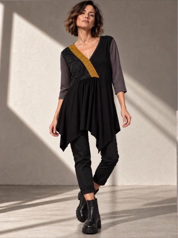 A black asymmetric jersey tunic in an arched doorway